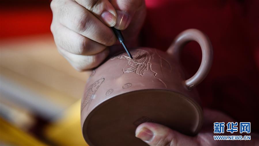 郭卉運用陶刻技藝在坭興陶表面雕刻