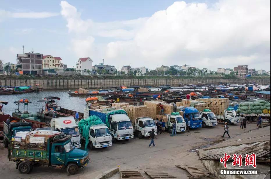 小貨車在東興互市貿易區排隊裝貨，河對岸是越南芒街市。