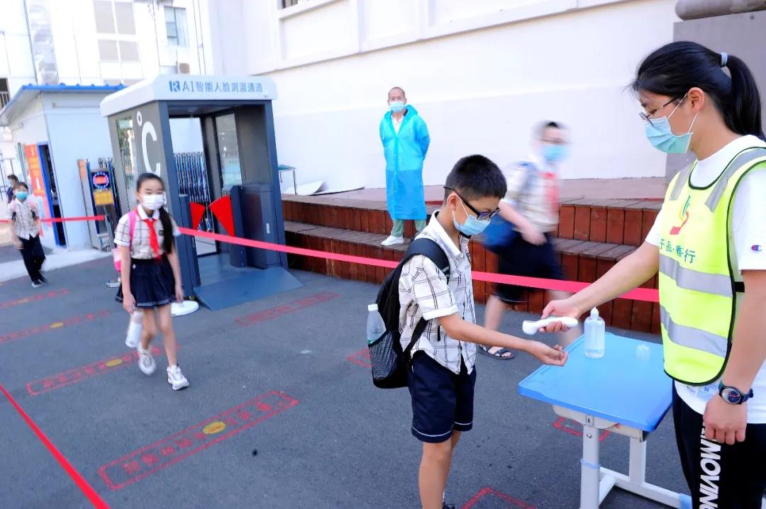 桂雅路小學桂花校區老師在校門給進入學校的學生測量體溫。