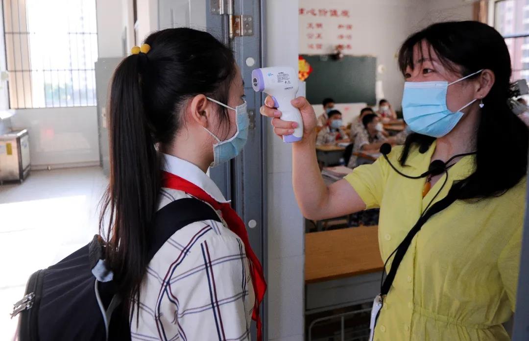 桂雅路小學桂花校區老師在校門給進入學校的學生測量體溫。