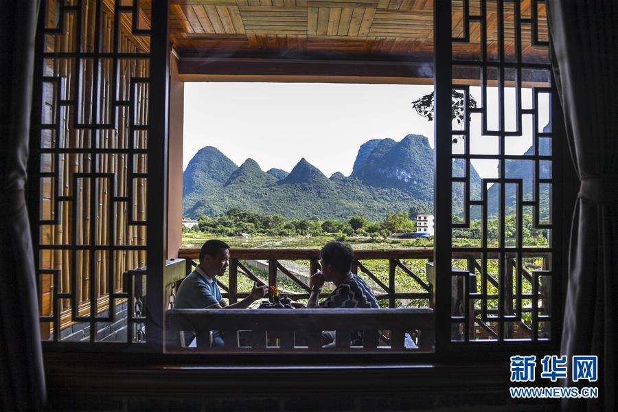 遊客在廣西陽朔縣一家民宿的陽台上喝茶聊天。