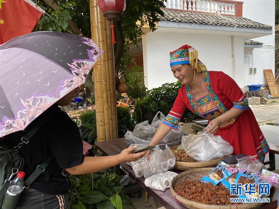 村民楊燕紅在家門口向客人推銷本地特產。
