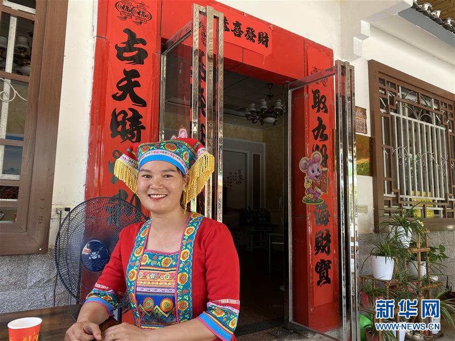 村民楊燕紅穿著民族服飾坐在家門口等待客人到來。