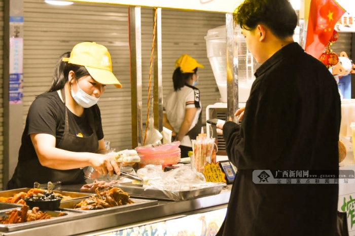 市民在南寧市西關夜市街購買小吃。