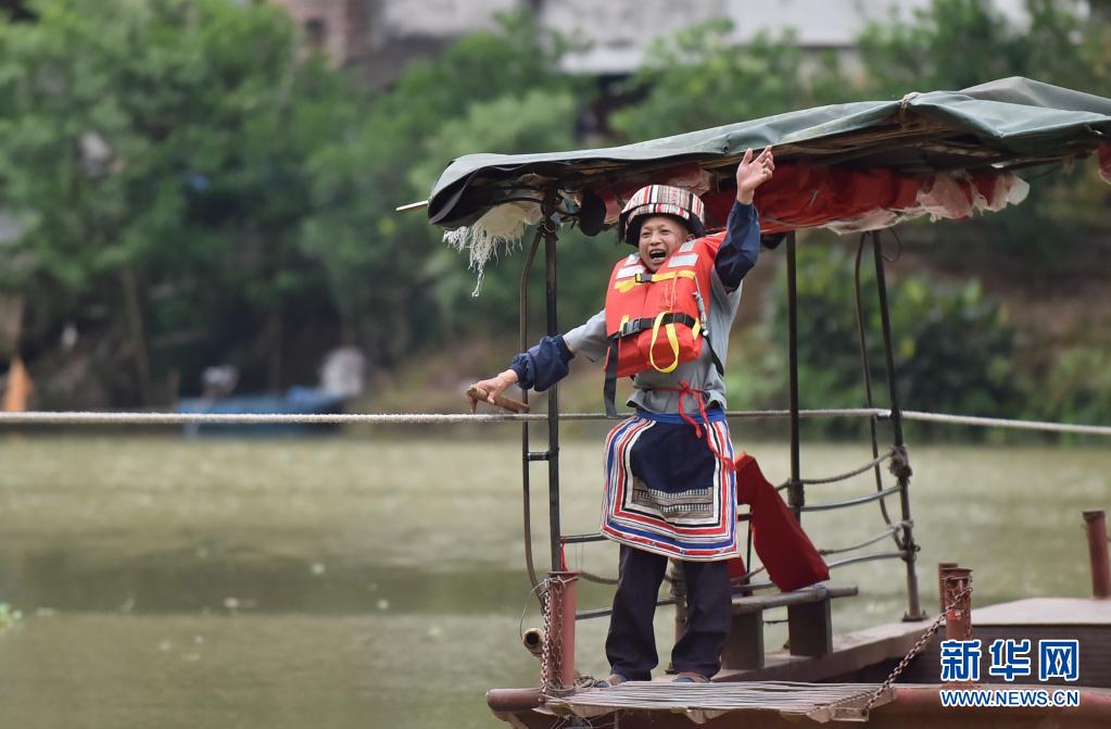 趙仕斌在渡船上向放學後來渡河的小學生揮手。