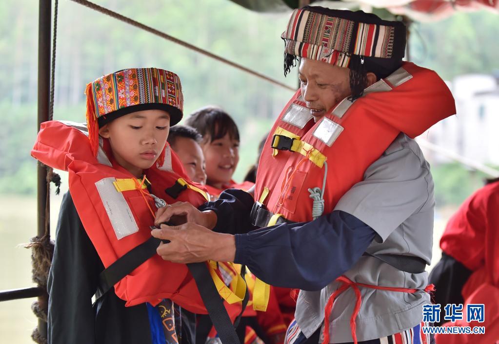 趙仕斌（右一）在渡船上幫助小學生穿戴救生衣。