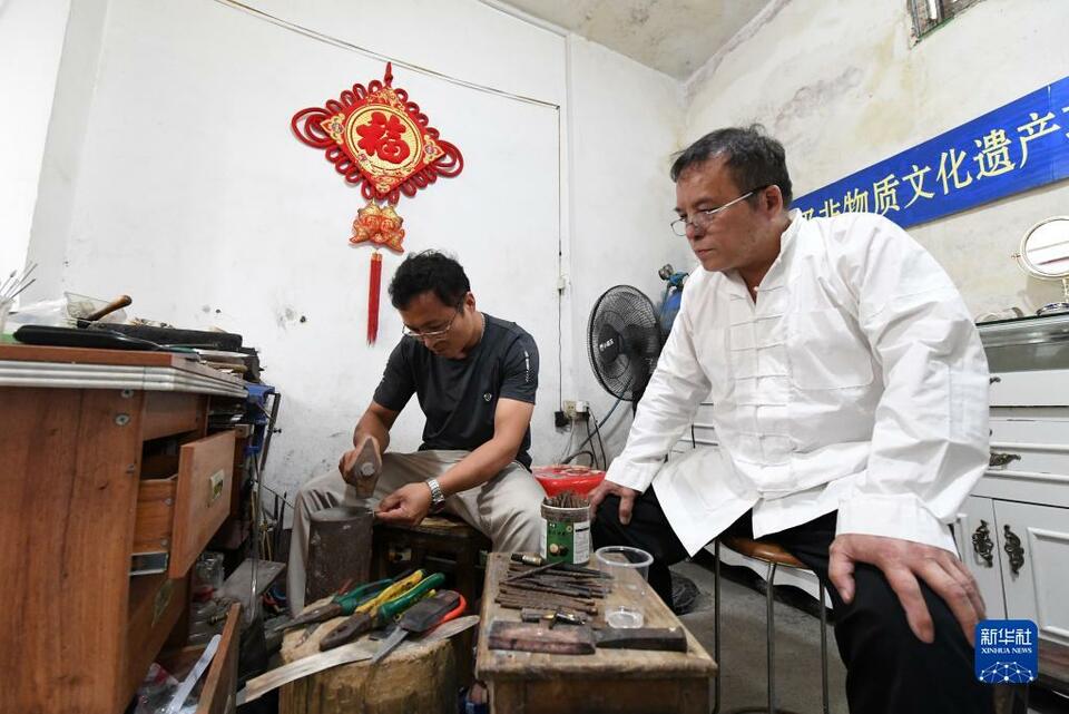 吳共能（右）在工作室看兒子吳維兵打造銀飾。