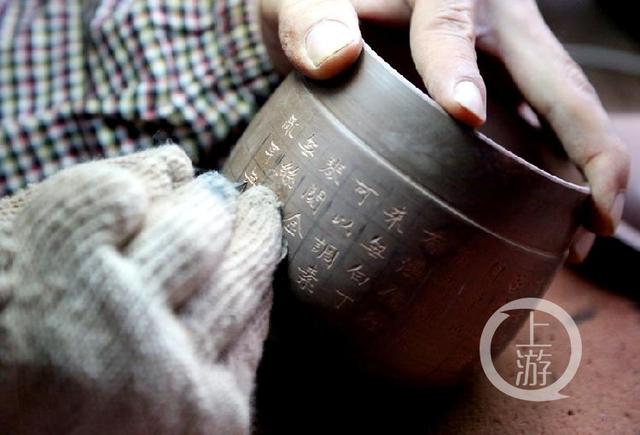 師傅在坭興陶杯上刻字。